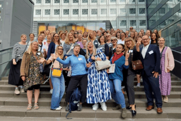 Kuvassa on Suomi-koulujen opettajia ympäri maailman iloisina ryhmäkuvassa rakennuksen portailla